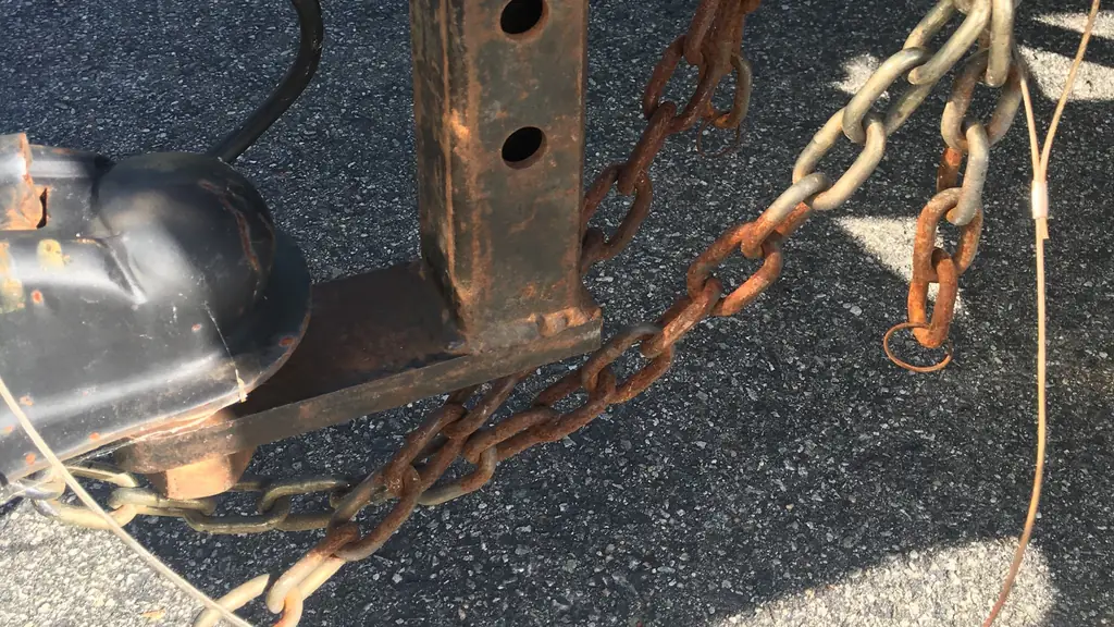 Rusted tow chains and a drop hitch shank lying on asphalt