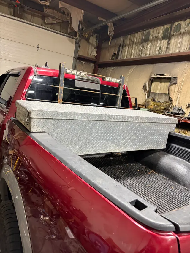 Red pickup with a diamond-plate toolbox and a Back Rack headache rack in the garage bay