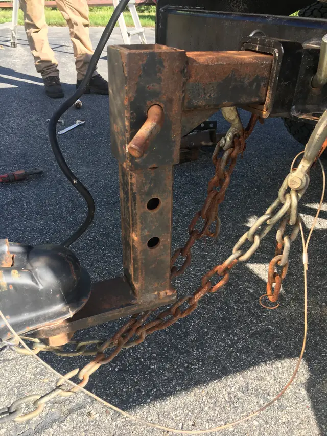 Rusted adjustable drop hitch and tow chains on asphalt at the Moosup yard